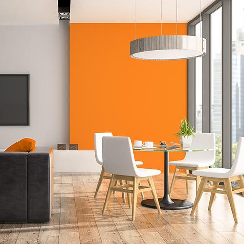 A living room design with a orange wall, dining set white and light wood. 