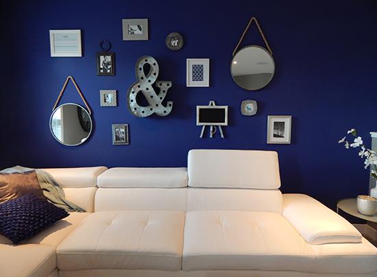 A cream/white sofa with bold background, and several decorations in the wall. 
