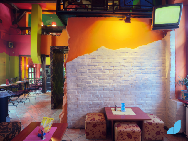 The interior of a cafe with colourful walls, wood tables and traditional style.